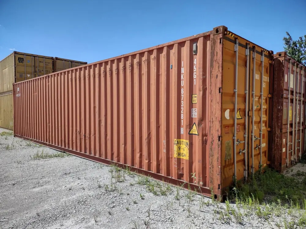 Used red 40ft high cube shipping container on a gravel lot